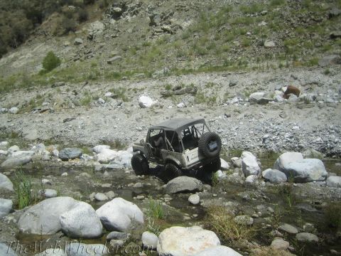 1987 Suzuki Samurai - Suzuki Samurai off-roading in a rocky stream bed, spare tire mounted on the back.