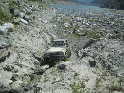 1987 Suzuki Samurai - A 1987 Suzuki Samurai drives through a , rocky terrain near a body of water.