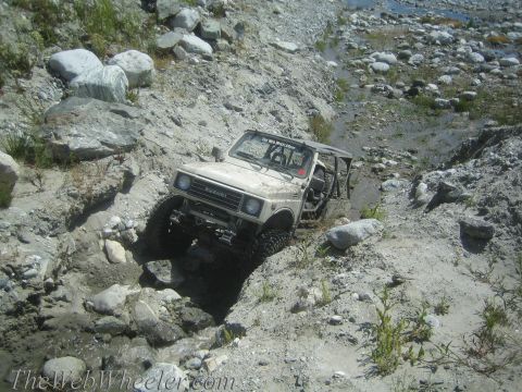 1987 Suzuki Samurai - A 1987 Suzuki Samurai tackles a challenging off-road course through a rocky, water-filled gully.