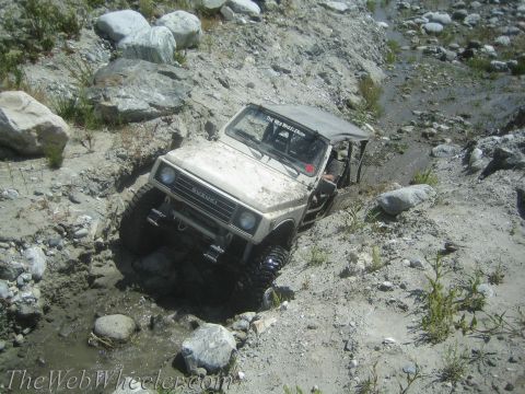 1987 Suzuki Samurai - A Suzuki Samurai tackles a challenging off-road trail, navigating through mud and rocks.