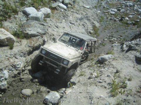 1987 Suzuki Samurai - Suzuki Samurai tackling a challenging off-road course with mud and rocks.