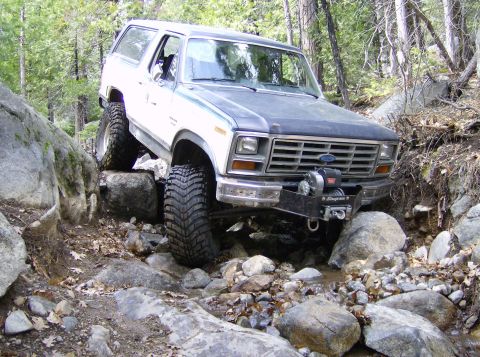 1986 Ford Bronco - This 1986 Ford Bronco is shown tackling a challenging off-road course with its tires climbing over large rocks.