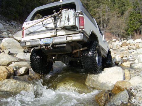 1986 Ford Bronco - This modified 1980s Ford Bronco is shown off-roading through a shallow, rocky creek.