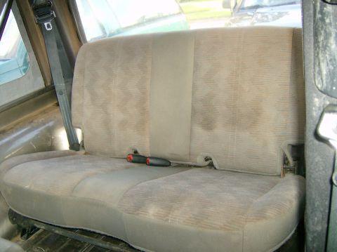 2004 Jeep Wrangler - The interior of a vehicle shows the rear seat and seatbelt, with some visible stains on the upholstery.