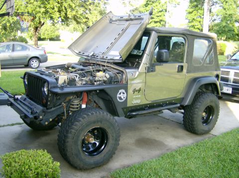 2004 Jeep Wrangler - A green Jeep Wrangler is parked outside with its hood open, revealing the engine compartment. Another vehicle is parked behind it.