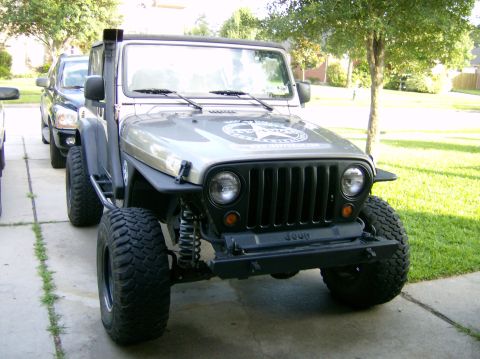2004 Jeep Wrangler - A silver Jeep Wrangler is parked in a driveway, showing its front grille and snorkel.