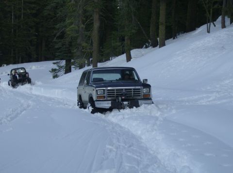 1986 Ford Bronco - A Ford Bronco navigates a snowy trail with another vehicle behind it.