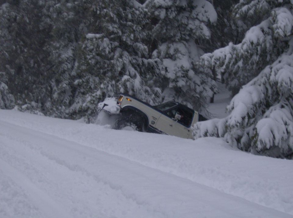 White SUV stuck in deep snow on a wooded slope
