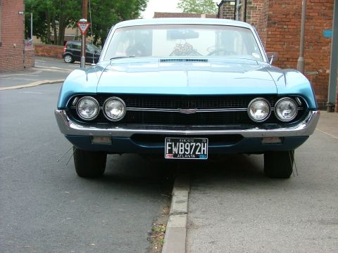 1970 Ford Ranchero - A blue 1970 Ford Ranchero is seen from the front, parked on a street with a curb.