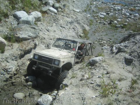 1987 Suzuki Samurai - A tan Suzuki Samurai navigates a challenging off-road course with a driver visible.