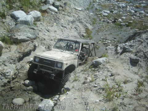 1987 Suzuki Samurai - This 1987 Suzuki Samurai is shown navigating a challenging off-road course with steep inclines and rocky obstacles.