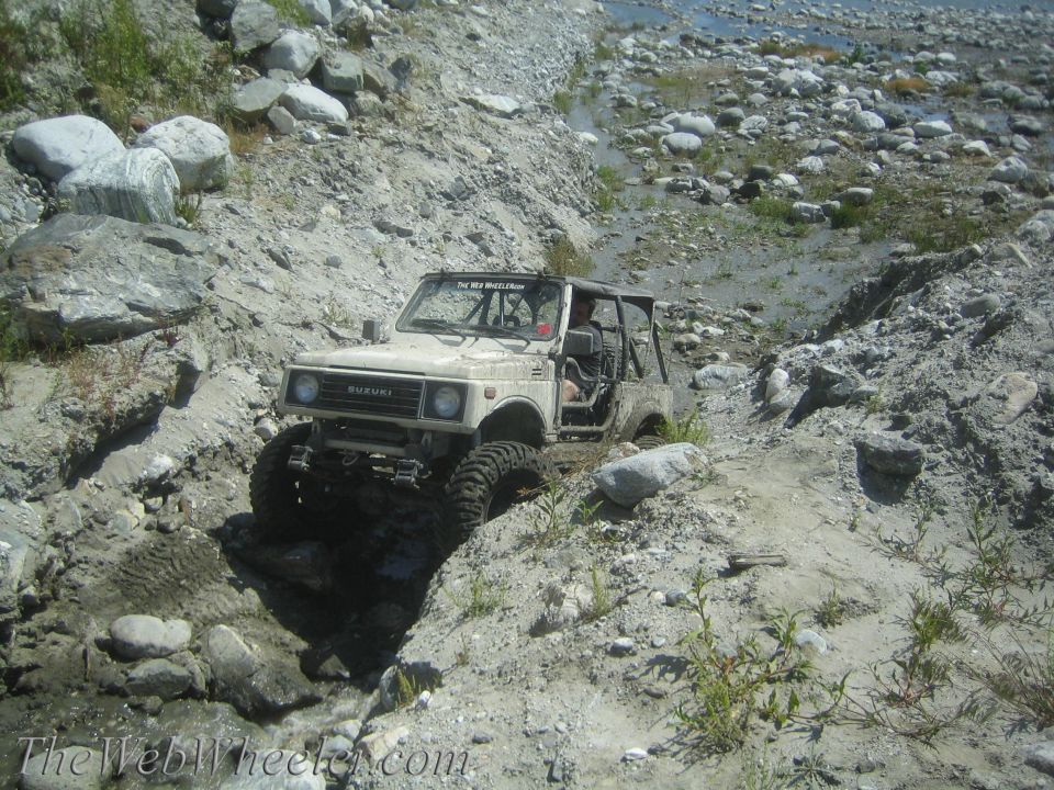 Suzuki Samurai navigating a rocky, wet trail. The Web Wheeler.com is visible