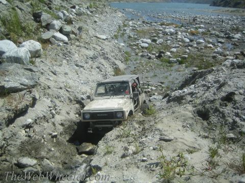 1987 Suzuki Samurai - A Suzuki Samurai navigates a challenging, rocky terrain near a body of water.