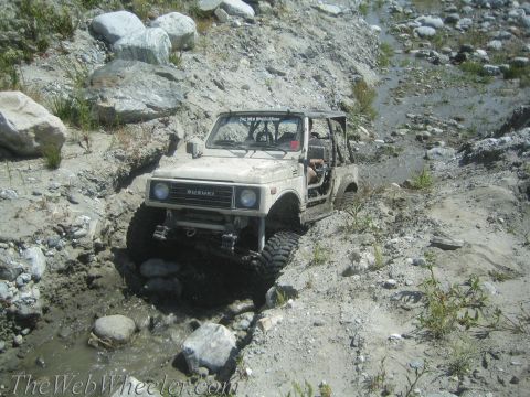 1987 Suzuki Samurai - A Suzuki Samurai tackles a challenging off-road course with steep, rocky inclines and water obstacles.
