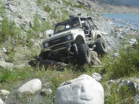 1987 Suzuki Samurai - A 1987 Suzuki Samurai navigates a challenging rocky path near a body of water.