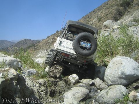 1987 Suzuki Samurai - Suzuki Samurai tackling a challenging off-road course with steep inclines and large boulders.
