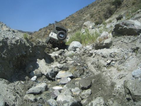 1987 Suzuki Samurai - This Suzuki Samurai is tackling a challenging off-road trail with steep, rocky inclines.