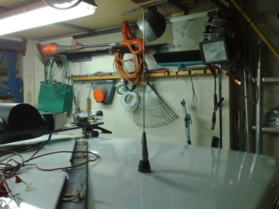 Garage workbench wall with hand tools, cords and a rake hanging