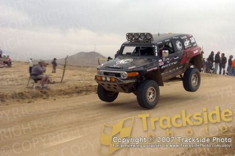 1992 Ford Explorer - A black Toyota FJ Cruiser with racing decals is captured mid-air during an off-road event.