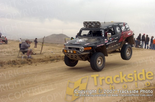Black Toyota FJ Cruiser off-roading, front wheels airborne, with racing decals