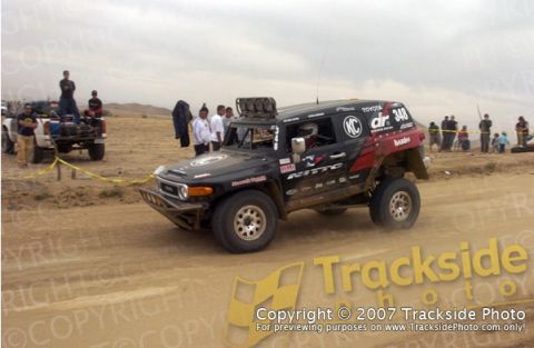 1992 Ford Explorer - A black Toyota FJ Cruiser, number 348, races on a dirt track with spectators in the background.
