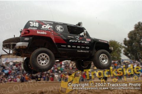1992 Ford Explorer - A Toyota FJ Cruiser jumps during a race, with spectators in the background.