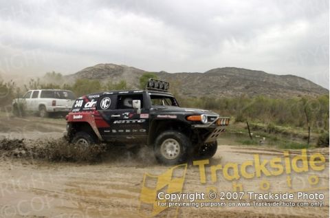 1992 Ford Explorer - A black Toyota FJ Cruiser navigates a muddy terrain, with another vehicle visible in the distance.