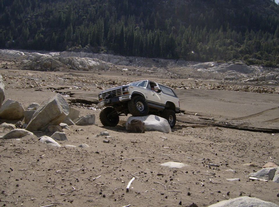White Ford Bronco with lifted suspension navigating large rocks off-road