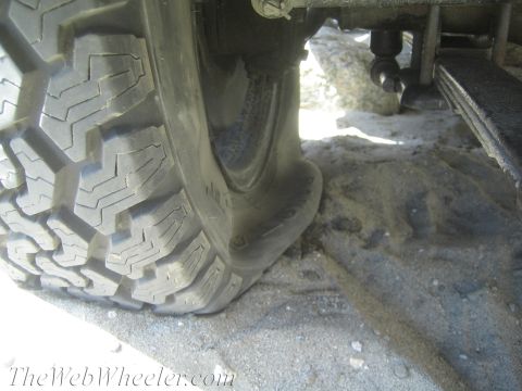 1987 Suzuki Samurai - A tire appears to be flat or deflated, resting on sandy terrain.