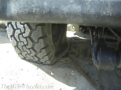 1987 Suzuki Samurai - Tire on sandy terrain, showing suspension components. The WebWheeler.com watermark is present.