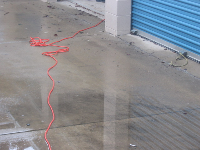 orange extension cord lying on wet concrete in front of a blue roll-up door