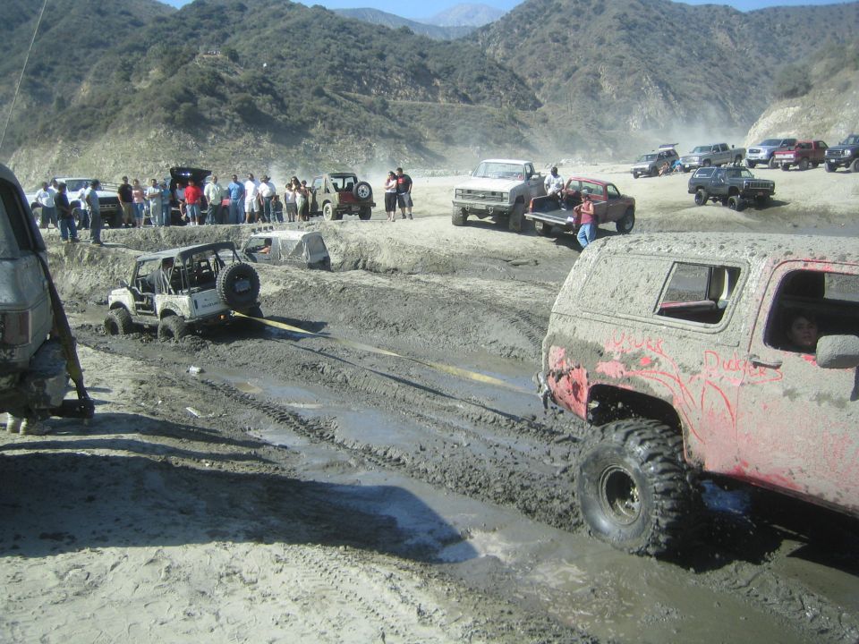 Muddy off-road vehicles being towed in a dry riverbed
