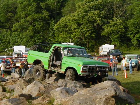 1990 Ford Bronco - Modified green Bronco navigating a rocky obstacle course with other vehicles present.