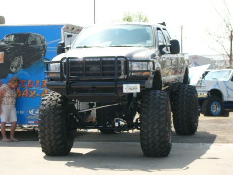1978 Ford Bronco - A lifted Ford F-Series truck with large off-road tires is parked at an outdoor event.