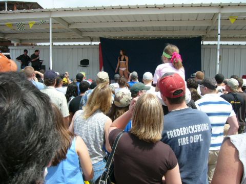 1978 Ford Bronco - A crowd gathers to watch a bikini contest on a stage under a covered pavilion.