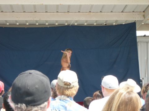 1978 Ford Bronco - A woman in a bikini poses on a stage in front of a blue curtain, with an audience watching.