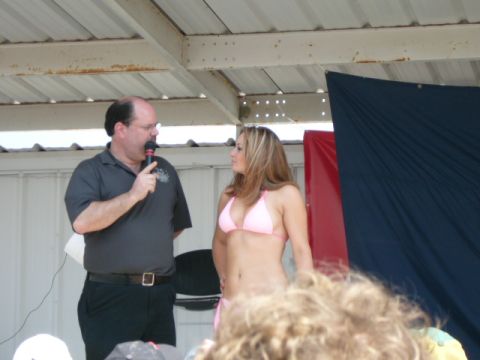 1978 Ford Bronco - A man holding a microphone speaks to a woman wearing a pink bikini on a stage, possibly during an event.