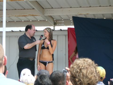 1978 Ford Bronco - A woman in a bikini is interviewed on stage during a contest, with an audience watching.