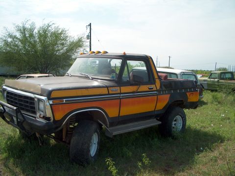 1979 Ford Bronco - This 1979 Ford Bronco, with its distinctive orange and yellow stripe pattern, sits in a junkyard, awaiting restoration.