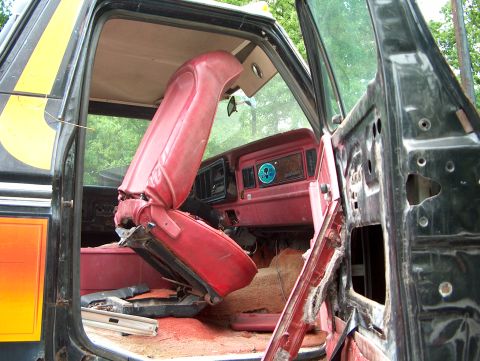 1979 Ford Bronco - Interior view of a 1979 Ford Bronco, showing a damaged red seat and door.