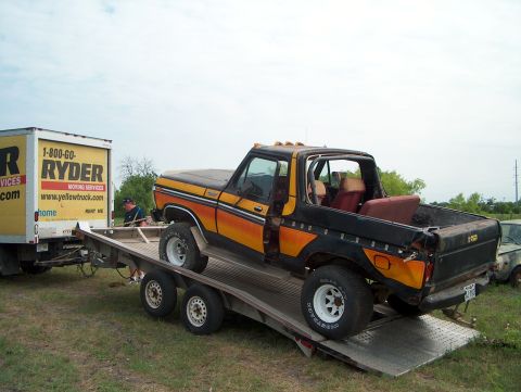 1979 Ford Bronco - A black and orange 1978 Ford Bronco is loaded onto a trailer, with a Ryder moving truck in the background.