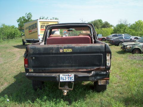 1979 Ford Bronco - Rear view of a 1979 Ford Bronco in a junkyard setting with other vehicles present.