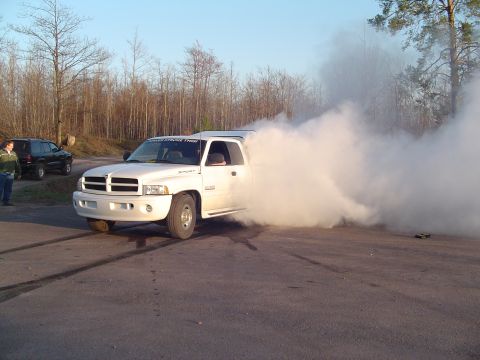 2000 Chevrolet Tahoe - A white Dodge Ram pickup truck is performing a burnout, generating a large cloud of smoke.