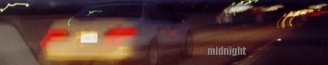 1993 Ford Taurus - A blurry nighttime photo captures the rear of a car, its taillights glowing and a license plate visible.