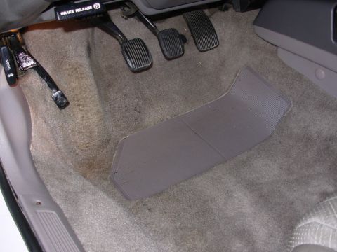 1995 Ford Taurus - Interior view of the footwell in a 1995 Ford Taurus, showing the brake release lever and pedals.