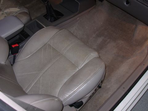 1995 Ford Taurus - The interior of a car features a light-colored leather passenger seat and beige carpeting on the floor.