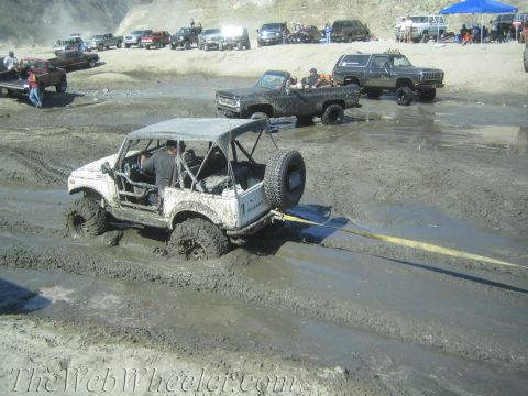 1987 Suzuki Samurai - A Suzuki Samurai is stuck in deep mud while other vehicles wait in the background.