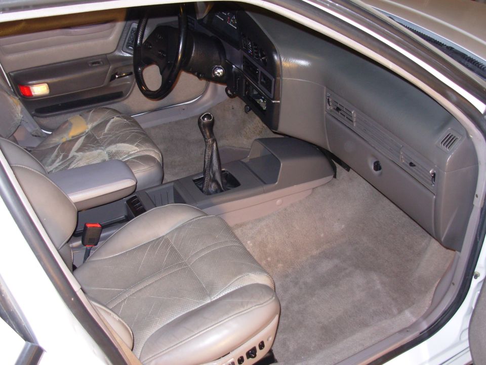 Interior of a car with worn leather seats and a manual transmission