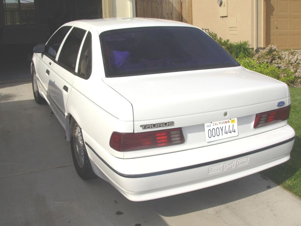 Rear view of a white 1995 Ford Taurus SHO sedan parked in a driveway