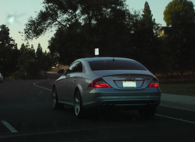 Silver Mercedes-Benz sedan driving on a road with trees in the background